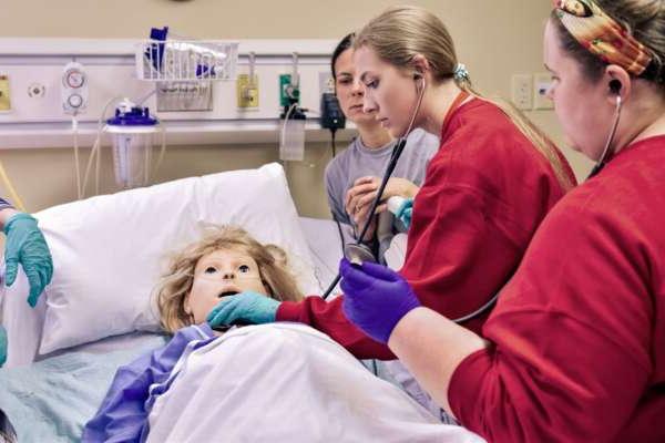 Nursing students assessing a mannequin's health